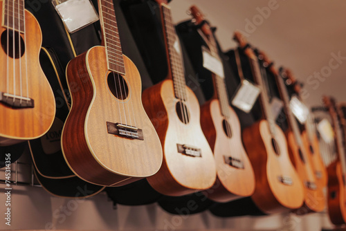 Many different acoustic ukulele hanging on wall of music shop. Close up.