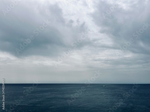 Cloudy seascape, sail boats silhouettes at the sea