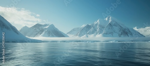 Snow-covered mountains loom majestically around a large body of water. The pristine white snow contrasts sharply with the deep blue of the water, creating a striking visual contrast.