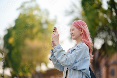 Young woman with long pink hair photographing among the city.