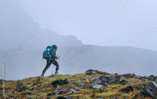 Lonely woman with backpack and trekking poles going by mountain route during Makalu Barun National Park near Tuli Kharka settlement trek in Nepal. Mountain hiking and active people concept image. photo