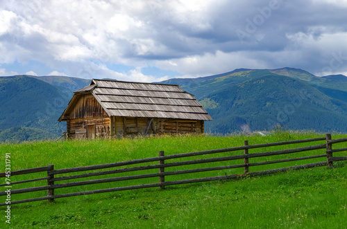 an old wooden lodge on a hill against a background of mountains. rural landscape