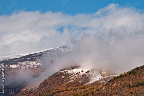 Russia. Mountain Altai. Fog turning into snow clouds around mountain peaks in the Chulyshman River valley in the south of Lake Teletskoye.