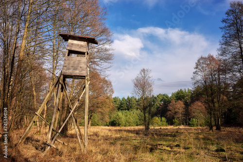 Photo of an elevated deer hunting blind by the woods.