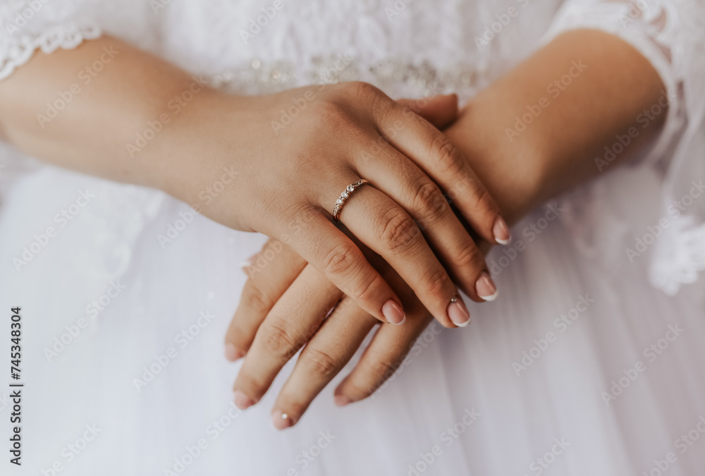 female hands bride lies on white wedding dress.