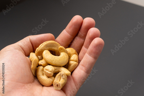 Hand holding a handful of cashew nuts.