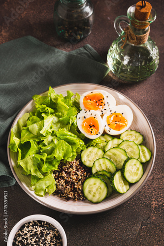 Fitness plate with quinoa, cucumber, egg and lettuce on the table vertical view