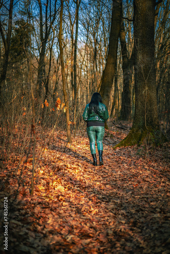 Kobieta ubrana na zielono spacerująca po lesie © Dominik Zarębski