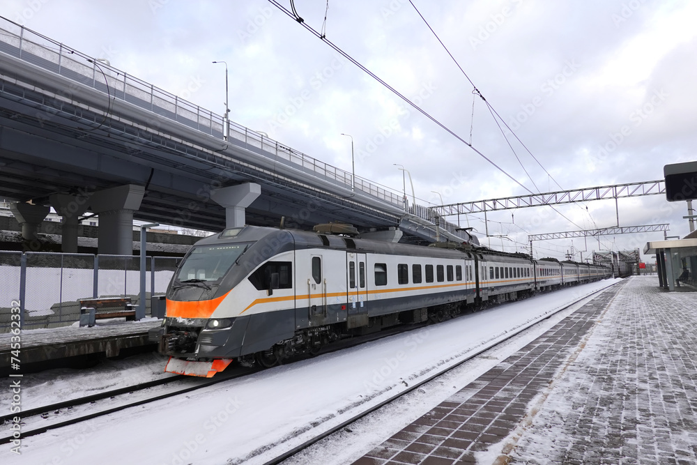 Regional passenger commuter train is arriving to station in cloudy winter day