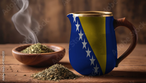 A teapot with the Bosnia and Herzegovina flag printed on it is on the table, next to it is a mug of tea and green tea is scattered. Concept of tea business, friendship, partnership