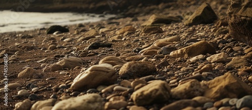 A rocky beach by a body of water in Jersey Channel Islands. The pebbly shoreline is surrounded by the ocean, creating a rugged coastal landscape.