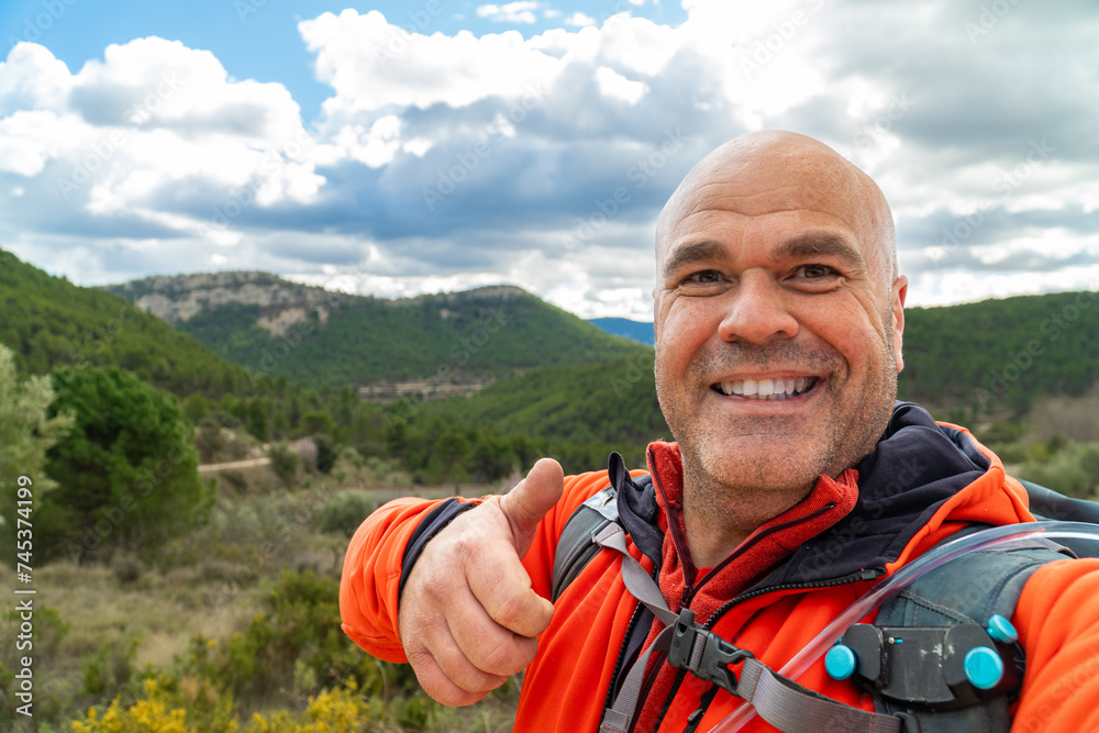 Happy hiker sign thumbs up taking a selfie outdoors