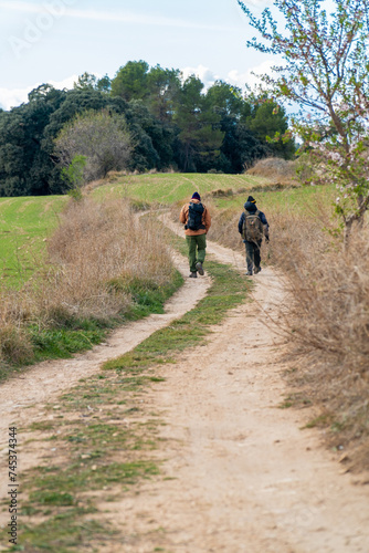 Two hikers walking on a beautiful path © MiguelAngel