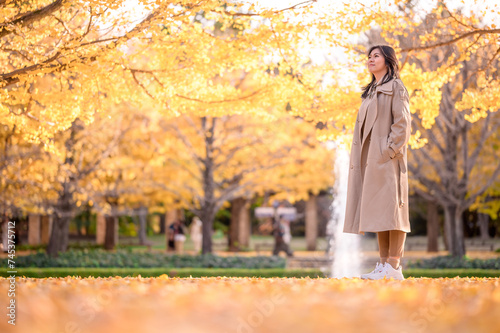 Happy Asian woman enjoy scenery of yellow ginkgo tree in autumn. Autumn park in Tokyo, Japan