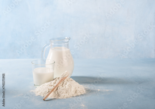 Milk in a glass jug with a pile of wheat flour next to it