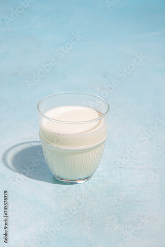 Glass of milk on blue background in sunlight