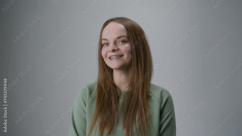 Braces on the teeth. Smiling red-haired woman looks at the camera on a white background