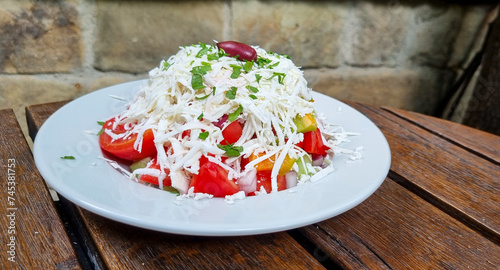 Traditional bulgarian dish - Shopska salad: fresh tomatoes, cucumbers, onion and cheese photo