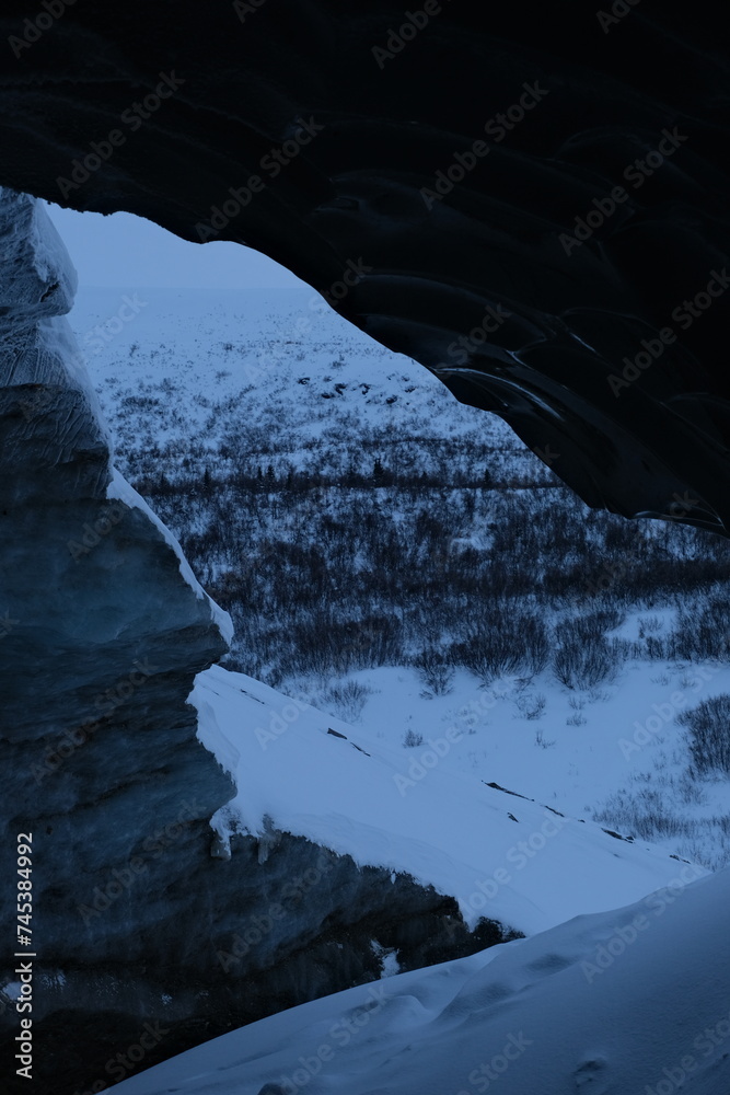 a person walking through a snow covered mountain under a cave