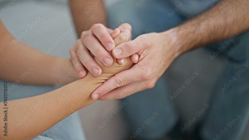 Beautiful couple sitting on sofa with hands together at home Beautiful couple sitting on sofa with hands together at home