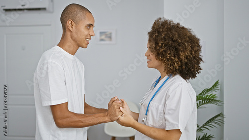 Doctor and patient enjoy a heartwarming, confident medical consultation, holding hands together at the bustling clinic, working towards a smiling, healthy, future.