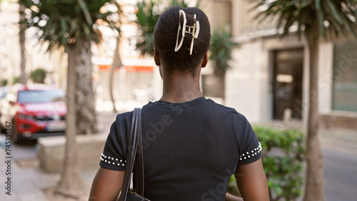 Beautiful african american woman, casually standing backwards on a city street, an attractive portrait of her back view.