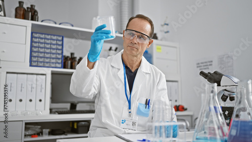 Serious  middle age man-scientist  diligently measuring liquid in a bustling laboratory - a major force in medical research progress