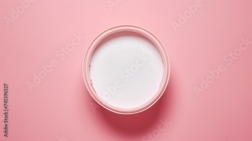 a glass of milk on a pink background with a reflection of the milk in the bottom half of the glass. photo