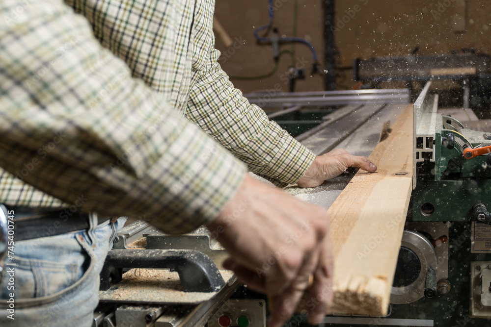 Horizontal photo carpenter manually feeding wood into saw. Business concept. Horizontal photo carpenter manually feeding wood into saw. Business concept.