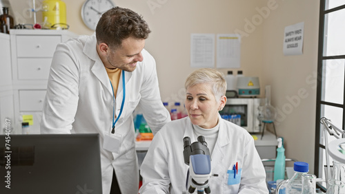 Woman and man scientists collaborating in a laboratory filled with equipment  discussing research findings.