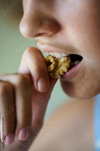 Anonymous girl eating healthy walnut kernel at home © javiindy