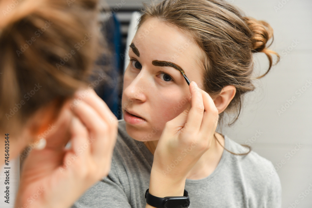 Woman paints her eyebrows with henna at home. Woman paints her eyebrows with henna at home.