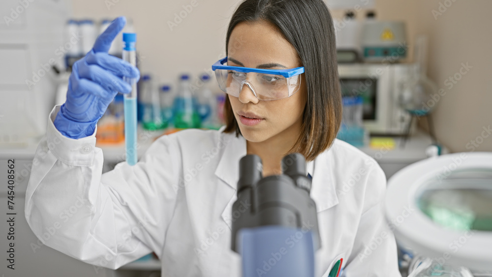 A young latina scientist examines a sample in a test tube at a laboratory, showcasing diversity in stem fields. A young latina scientist examines a sample in a test tube at a laboratory, showcasing diversity in stem fields.