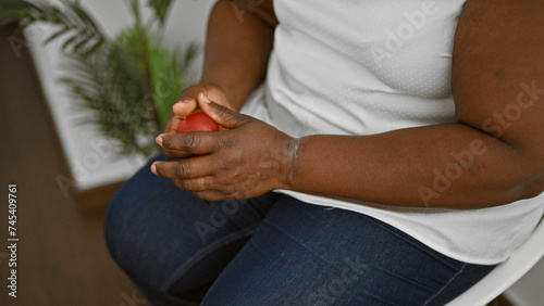 Stressed african american woman pressing anti stress ball in waiting room, nervously awaiting meeting or interview, hands packed with anxiety