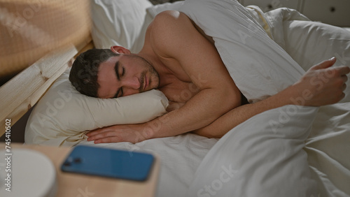 Hispanic man sleeping peacefully in a cozy bedroom, symbolizing relaxation and comfort. © Krakenimages.com