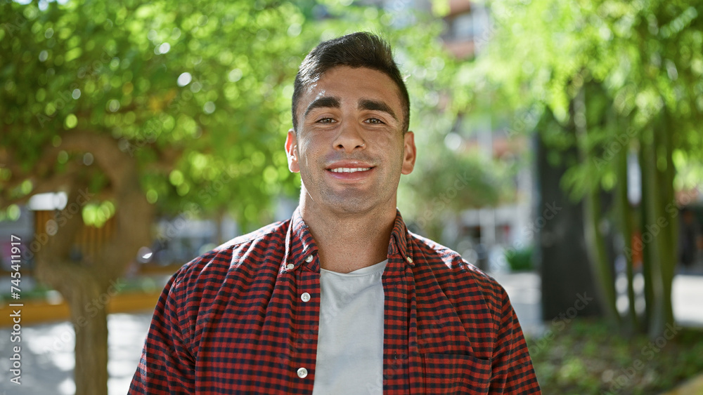 Confident young hispanic man, standing and smiling happily in outdoor city park, portrait of positive joyous expression, attractive, handsome, cheerful adult, enjoying nature, exuding confidence Confident young hispanic man, standing and smiling happily in outdoor city park, portrait of positive joyous expression, attractive, handsome, cheerful adult, enjoying nature, exuding confidence