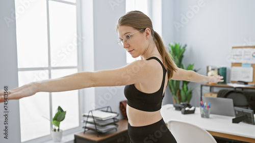A woman stretching in an office environment, indicating a break from work or health-conscious office lifestyle.