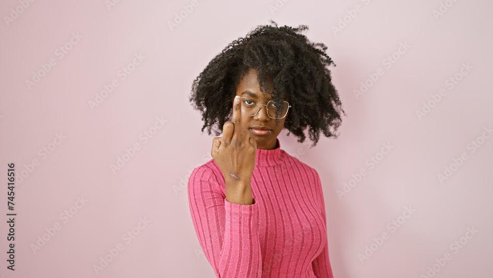 African american woman with glasses in pink sweater posing indoors with neutral background African american woman with glasses in pink sweater posing indoors with neutral background