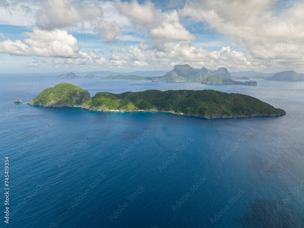 Inambuyod Island surrounded by blue sea. Blue sky and clouds. El Nido, Philippines.