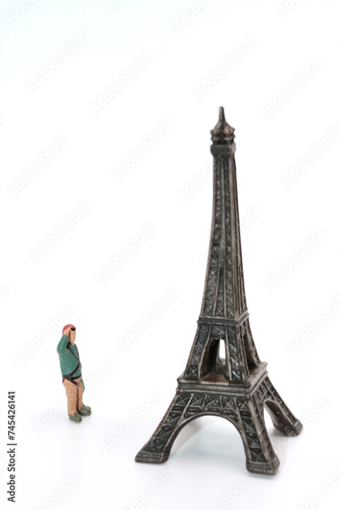 miniature figurine of an hiker looking at Eiffel Tower in Paris on a white background