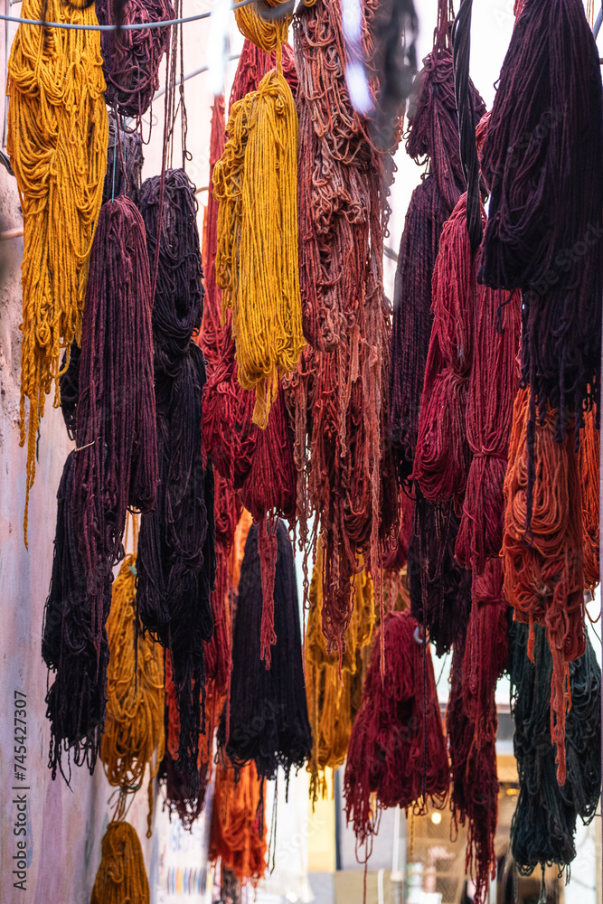 Colorful hanging fiber threads yarn for weaving handcrafted rugs, scarfs, and blankets in souk media Marrakesh, Morocco