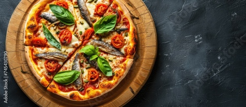 A top-down view of a homemade sardine pizza resting on a round wooden platter, set against a dark grey background.