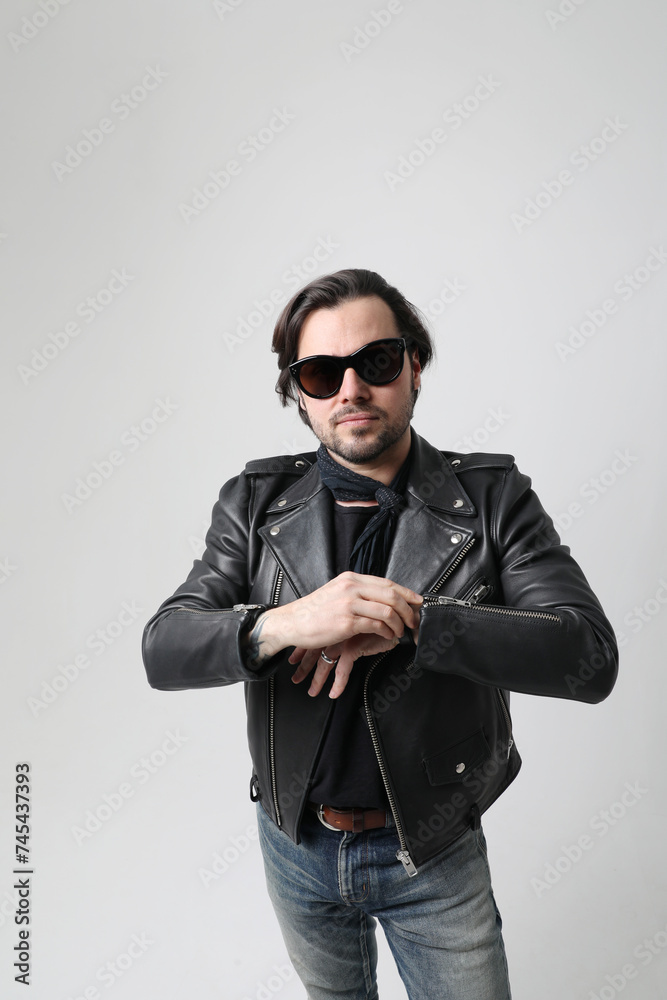 Obraz premium Stylish bearded young man wearing biker jacket posing indoor. Vertical mock-up.