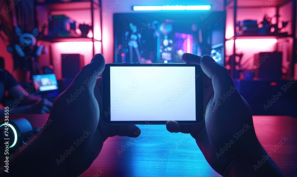 Two hands holding a mobile device with horizontal white screen, gamer room background - obrazy, fototapety, plakaty 