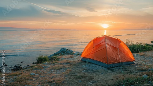 Orange camping tent on a shore in a morning light