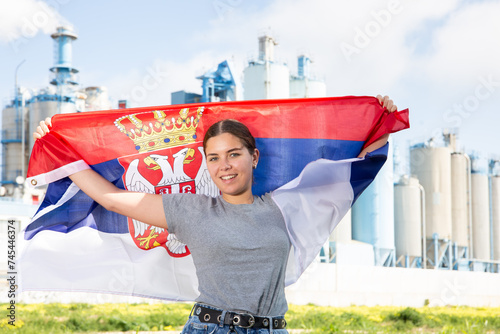 Fotografie Cheerful girl with serbian flag standing in front of factory