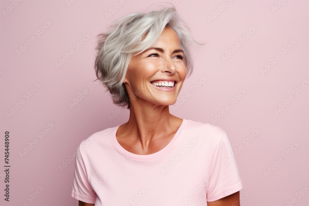 Mature woman with white hair. Portrait of happy mature woman looking at camera and smiling while standing against pink background Mature woman with white hair. Portrait of happy mature woman looking at camera and smiling while standing against pink background