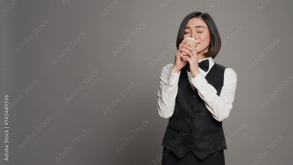 Asian receptionist serving coffee cup in front of camera, taking a break and enjoying hot refreshment. Hotel administrator drinking caffeine beverage, tourism concept. Camera A. Asian receptionist serving coffee cup in front of camera, taking a break and enjoying hot refreshment. Hotel administrator drinking caffeine beverage, tourism concept. Camera A.