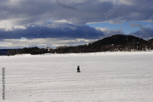 Östersund, Sweden 2024.02.25 Park and lake in winter in the city. Winter park in Östersund. People sunbathe, barbecue, ski, and skate.