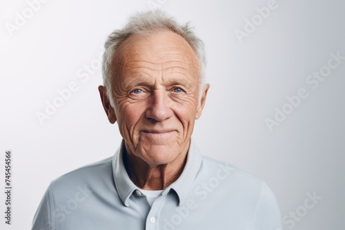 Portrait of an elderly man in a blue shirt on a gray background
